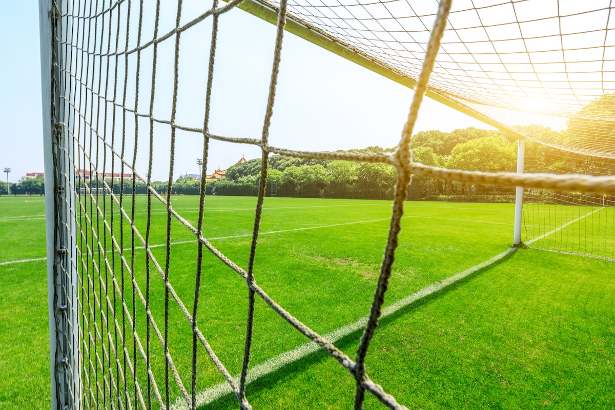 Soccer field with goal net under blue sky